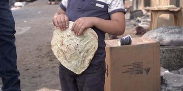 A young boy holds some bread on a street in North Gaza. A young boy holds some bread on a street in North Gaza.