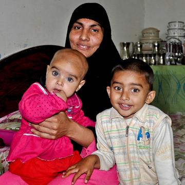 Mother Sobia smiles while sitting with her children Fatima, age 9 months, and Abdullah, age 3, inside their home in Pakistan. Mother Sobia smiles while sitting with her children Fatima, age 9 months, and Abdullah, age 3, inside their home in Pakistan.