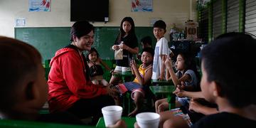 Children in the Philippines sit in a classroom with a ±¬ÁÏÿÈÕ´óÈü staff member Children in the Philippines sit in a classroom with a ±¬ÁÏÿÈÕ´óÈü staff member