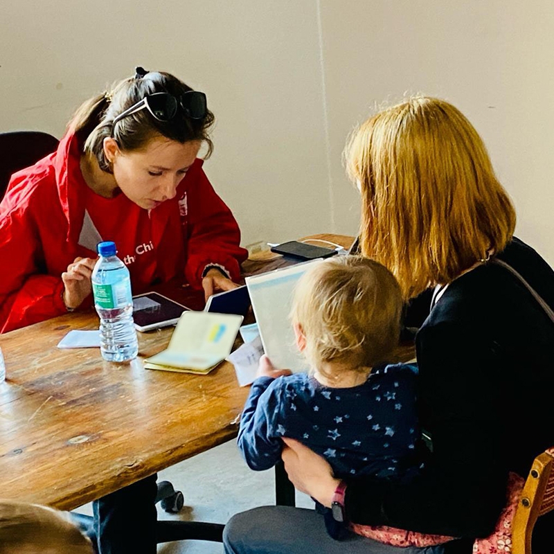 In Poland, a Ukrainian refugee family sits at a table to complete paperwork to receive cash assistance. 