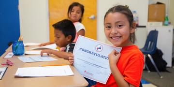 USA, girl in an orange shirt holds up a "congratulations certificate" USA, girl in an orange shirt holds up a "congratulations certificate"