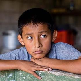 11-year-old Anderson rests his head on his hands while sitting inside his home in El Salvador. 11-year-old Anderson rests his head on his hands while sitting inside his home in El Salvador.