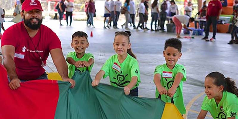 A group of children along with a Save the Children worker participate in Journey of Hope at the Mulitas Community Center in Puerto Rico, using the parachute to communicate their feelings following Hurricane Maria. A group of children along with a Save the Children worker participate in Journey of Hope at the Mulitas Community Center in Puerto Rico, using the parachute to communicate their feelings following Hurricane Maria.