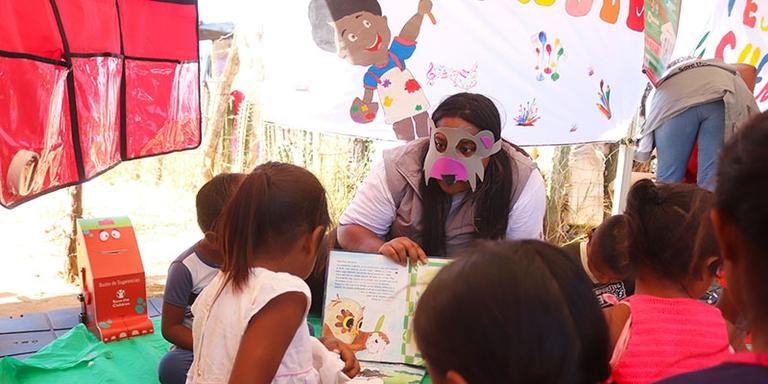 A Save the Children reads to a group of young children A Save the Children reads to a group of young children