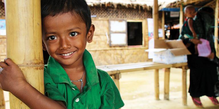 A young boy in a green shirt leans against a pole. A young boy in a green shirt leans against a pole.
