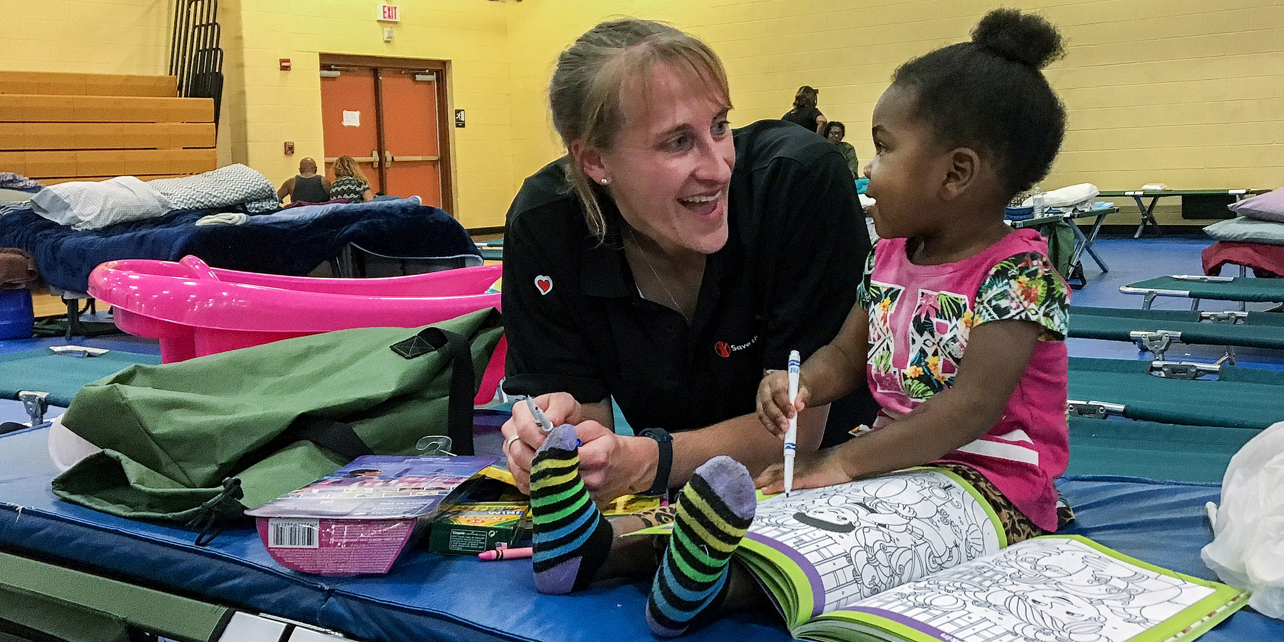 Sarah Thompson, Director of Preparedness for Save the Children, colors with a 2-year-old girl at a s