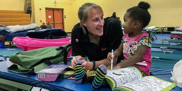 Sarah Thompson, Director of Preparedness for Save the Children, colors with a 2-year-old girl at a s Sarah Thompson, Director of Preparedness for Save the Children, colors with a 2-year-old girl at a s