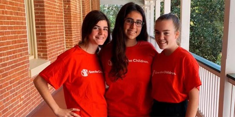 Three high school students stand together in Save the Children t-shirts. Three high school students stand together in Save the Children t-shirts.
