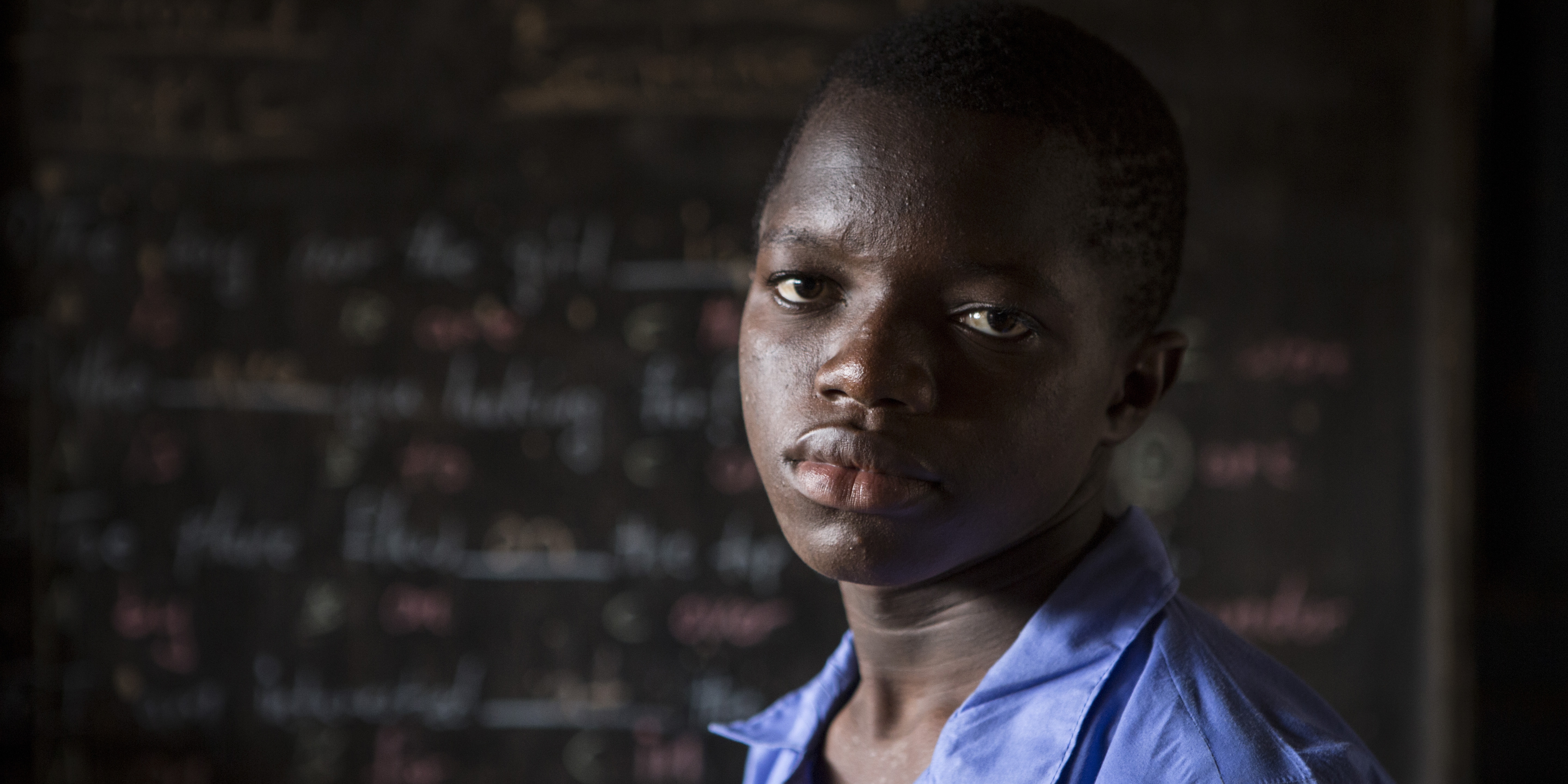 A 15-year-old boy stands alone solemnly looking into the camera. The young boy’s older brother died tragically from Ebola, leaving him vulnerable to both the disease and it’s devastating impact. Save the Children has been working in West Africa since 1987 to provide counseling and support services to children and families affected by the Ebola Crisis. Photo credit: Jonathan Hyams / Save the Children, July 2015.