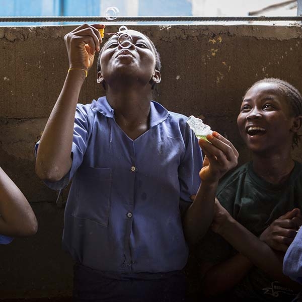 Girls in blue school uniforms enjoy blowing bubbles during a break at school. Girls in blue school uniforms enjoy blowing bubbles during a break at school.
