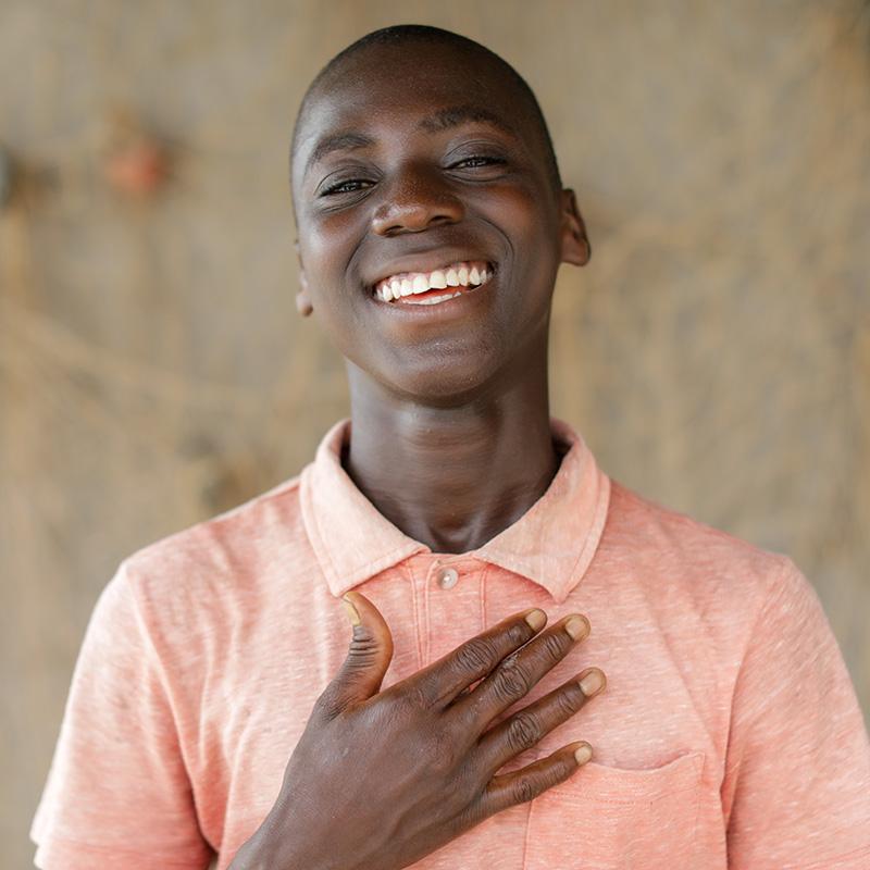 A boy with his hand on his chest wearing an orange shirt