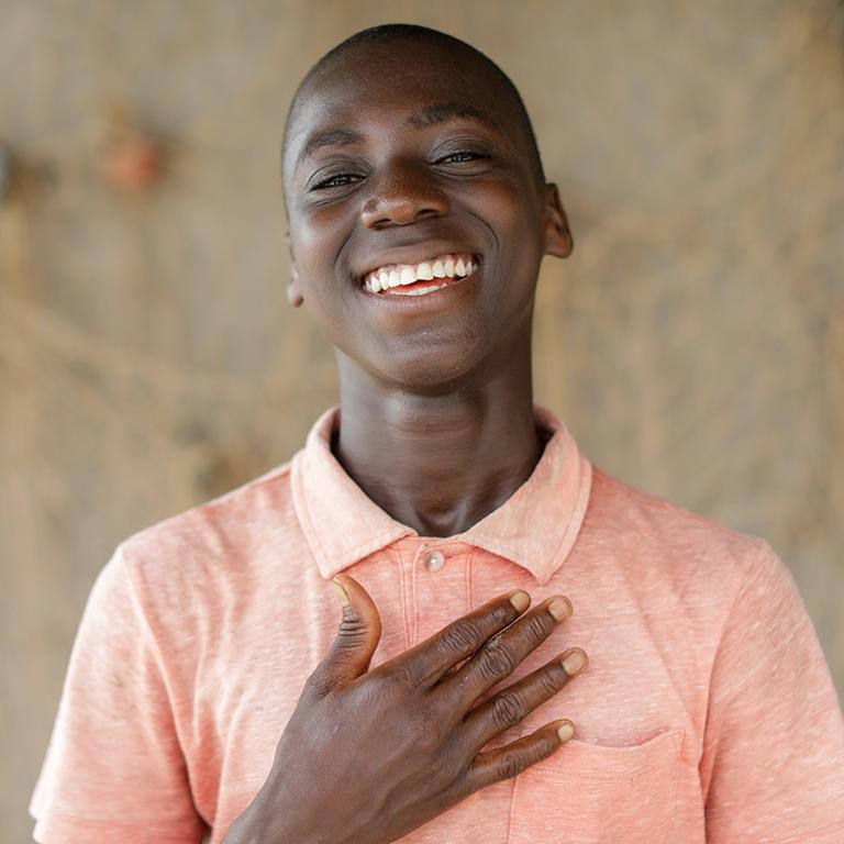 A boy with his hand on his chest wearing an orange shirt A boy with his hand on his chest wearing an orange shirt
