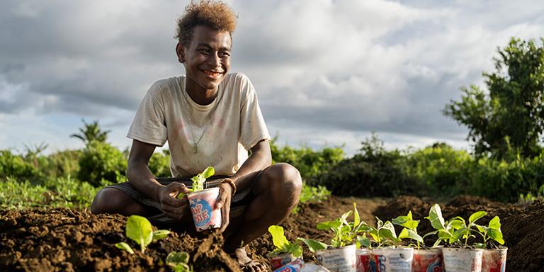 A teenage boy shows plants that his family is growing in the Solomon Islands. A teenage boy shows plants that his family is growing in the Solomon Islands.