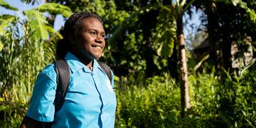 A teenage girl walks home from school with her backpack in the Solomon Islands. A teenage girl walks home from school with her backpack in the Solomon Islands.