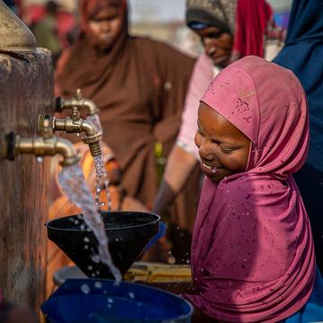 A girl wearing pink collects clean water from a water station A girl wearing pink collects clean water from a water station