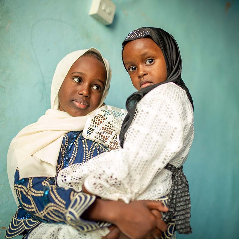 In Somalia, an older sibling holds her younger sibling in her arms. In Somalia, an older sibling holds her younger sibling in her arms.
