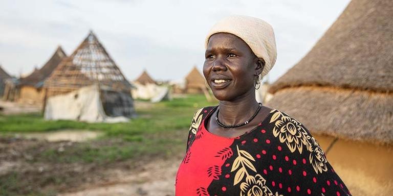 South Sudan, a woman and a red and black dress looks away from the camera South Sudan, a woman and a red and black dress looks away from the camera