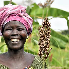 A South Sudanese farmer smiles standing among her crops A South Sudanese farmer smiles standing among her crops