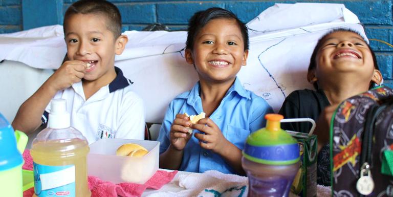 Three boys smile and laugh while sitting a table with snacks. Three boys smile and laugh while sitting a table with snacks.