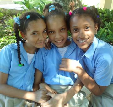 Three girls who are sponsored by Save the Children pose for a photograph in the Dominican Republic Three girls who are sponsored by Save the Children pose for a photograph in the Dominican Republic