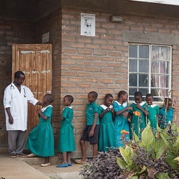 Children stand waiting in line to enter a school clinic