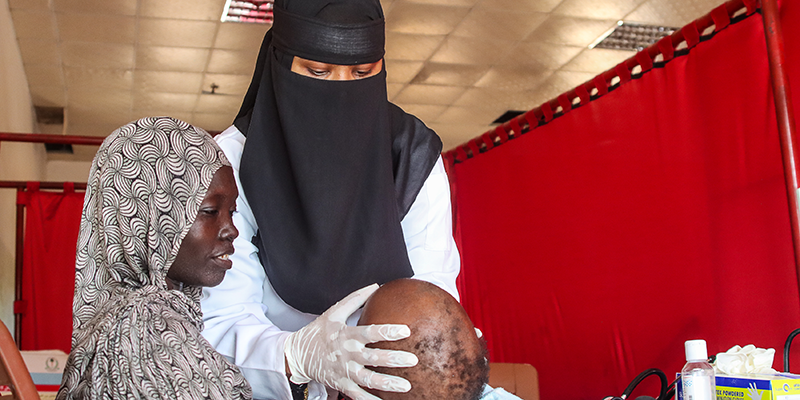 Baby Jamaal sits on his mother's lap and receives medical care at a clinic in Sudan