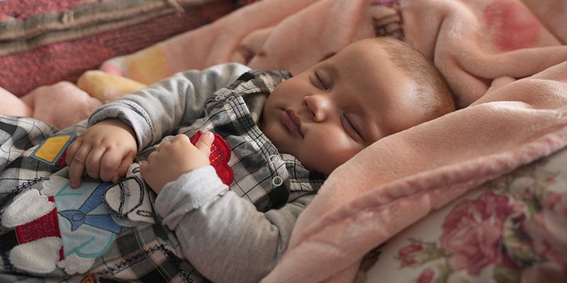Bilal*, 4 months, sleeping peacefully in his cot
