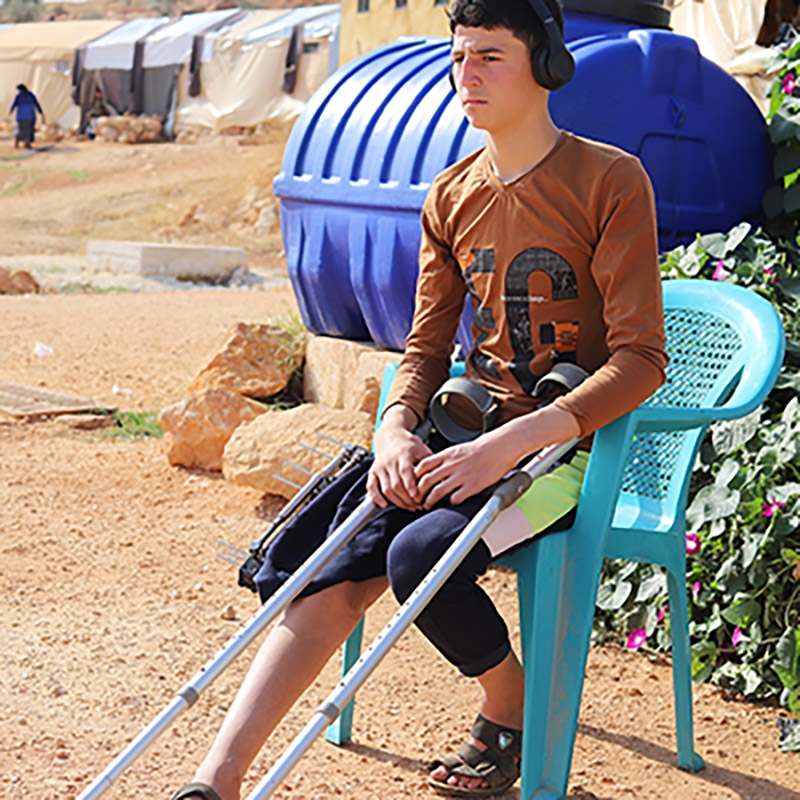 Syria, a teenage boy sits outside his tent listening to music. Syria, a teenage boy sits outside his tent listening to music.
