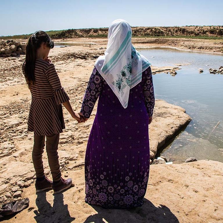 Syria, a mother and daughter look out over a river after a drought Syria, a mother and daughter look out over a river after a drought