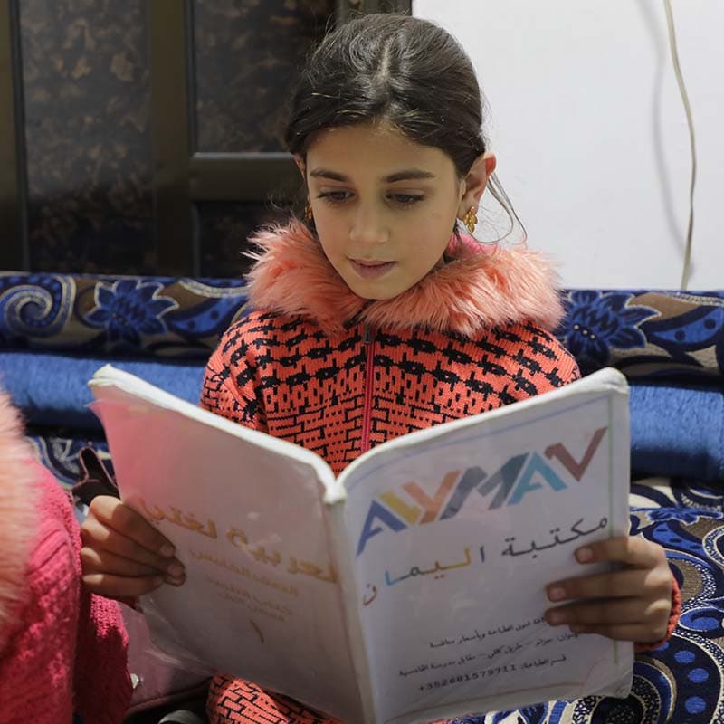 A girl reading in a Save the Children supported learning space