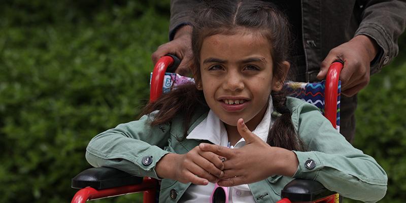 A girl in a white shirt and green jacket sits in a wheelchair in Syria A girl in a white shirt and green jacket sits in a wheelchair in Syria