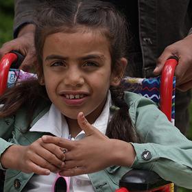A girl in a white shirt and green jacket sits in a wheelchair in Syria A girl in a white shirt and green jacket sits in a wheelchair in Syria