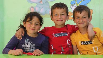 Three children sit and smile for the camera in Syria Three children sit and smile for the camera in Syria