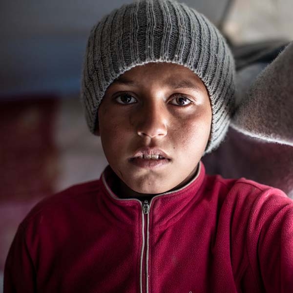 A 12-year old boy stands alone in a displacement camp, North East Syria. A 12-year old boy stands alone in a displacement camp, North East Syria.