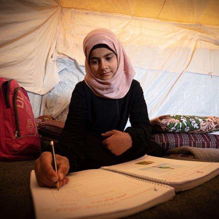 A girl does her homework in a refugee camp in north east Syria A girl does her homework in a refugee camp in north east Syria