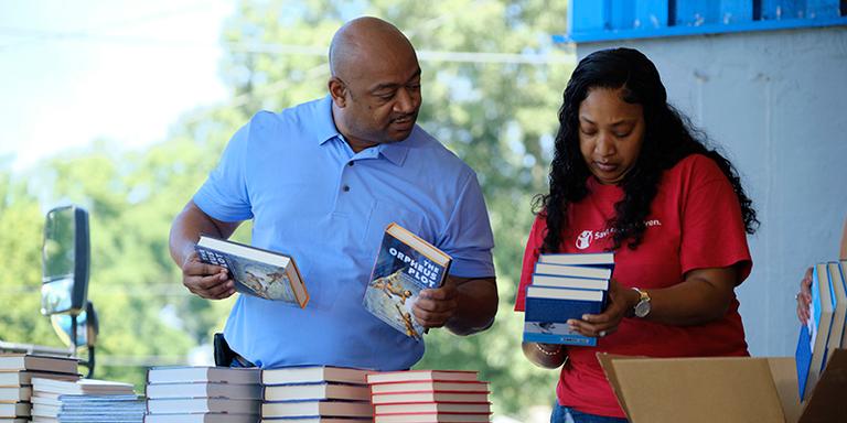 Save the Children staff and volunteers help their local community to organize books at a book distribution event. Save the Children staff and volunteers help their local community to organize books at a book distribution event.