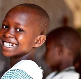 A 9-year-old schoolgirl in Uganda smiles brightly as she practices writing numbers on a chalkboard in her classroom thanks to a charity for children's education. Photo credit: Jordan. J. Hay, 2012. A 9-year-old schoolgirl in Uganda smiles brightly as she practices writing numbers on a chalkboard in her classroom thanks to a charity for children's education. Photo credit: Jordan. J. Hay, 2012.