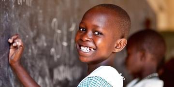 A 9-year-old schoolgirl in Uganda smiles brightly as she practices writing numbers on a chalkboard in her classroom thanks to a charity for children's education. Photo credit: Jordan. J. Hay, 2012. A 9-year-old schoolgirl in Uganda smiles brightly as she practices writing numbers on a chalkboard in her classroom thanks to a charity for children's education. Photo credit: Jordan. J. Hay, 2012.