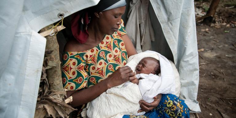 A foster mother, Theresa, cradles a newborn in a refugee settlement of Rwamwanja, Uganda. Theresa has 3 children of her own, but is helping care for the baby and her 5 siblings after the mother died from childbirth complications. The children’s father – a solider – was in a military hospital after being shot in the leg amid violence in the Democratic Republic of the Congo. Photo credit: Rebecca Vassie/Save the Children, March 2014. A foster mother, Theresa, cradles a newborn in a refugee settlement of Rwamwanja, Uganda. Theresa has 3 children of her own, but is helping care for the baby and her 5 siblings after the mother died from childbirth complications. The children’s father – a solider – was in a military hospital after being shot in the leg amid violence in the Democratic Republic of the Congo. Photo credit: Rebecca Vassie/Save the Children, March 2014.