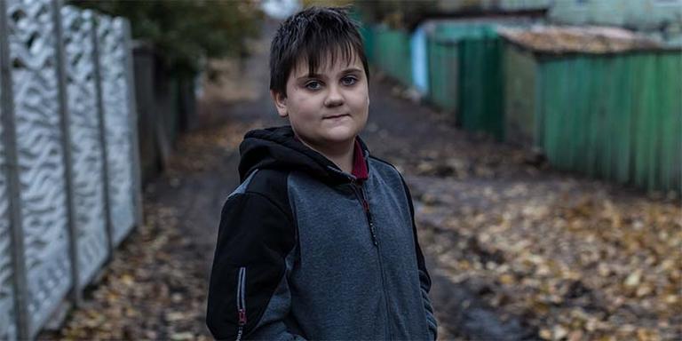 In Ukraine, a boy stands alone against a dark background. In Ukraine, a boy stands alone against a dark background.