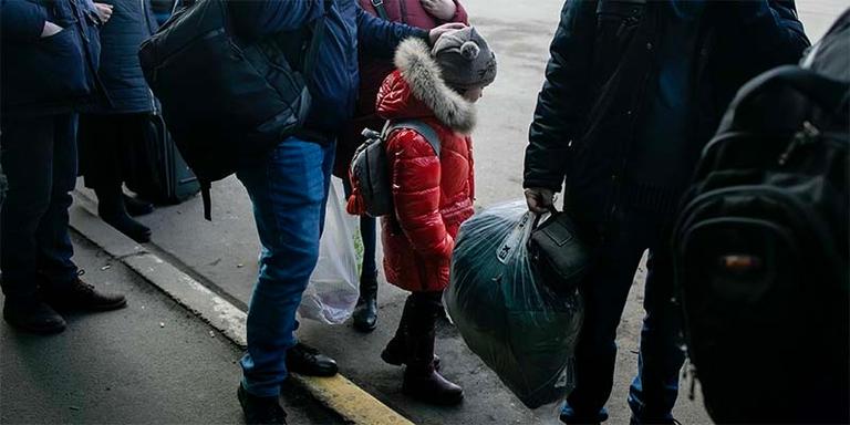 In Ukraine, a group of people stand in line outside in the cold. In Ukraine, a group of people stand in line outside in the cold.