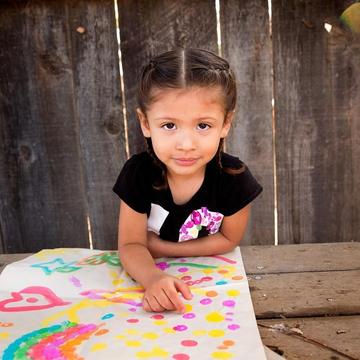 A 3-year old girl named Analia sits at a picnic table outside and displays a colorful painting in front of her. The girl and her mom participated in several learning-based activities taught to them during a home visit as part of Save the Children’s signature Early Steps to School Success program. Photo credit: Save the Children, Nov 2017. A 3-year old girl named Analia sits at a picnic table outside and displays a colorful painting in front of her. The girl and her mom participated in several learning-based activities taught to them during a home visit as part of Save the Children’s signature Early Steps to School Success program. Photo credit: Save the Children, Nov 2017.