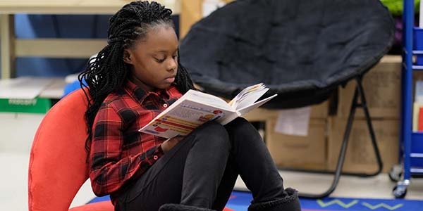 A girl sits in a beanbag chair reading a book. A girl sits in a beanbag chair reading a book.