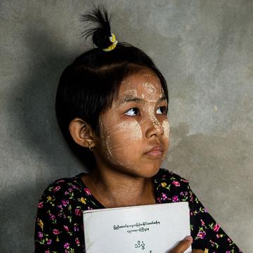 A young girl holding a book looking off into the distance. A young girl holding a book looking off into the distance.