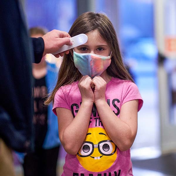 A student gets her forehead temperature checked in the hallway of a school in Tennessee. A student gets her forehead temperature checked in the hallway of a school in Tennessee.