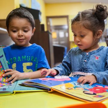 Two children read books inside a classroom Two children read books inside a classroom
