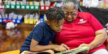 In Mississippi, a young boy reads a book with a Save the Children volunteer In Mississippi, a young boy reads a book with a Save the Children volunteer