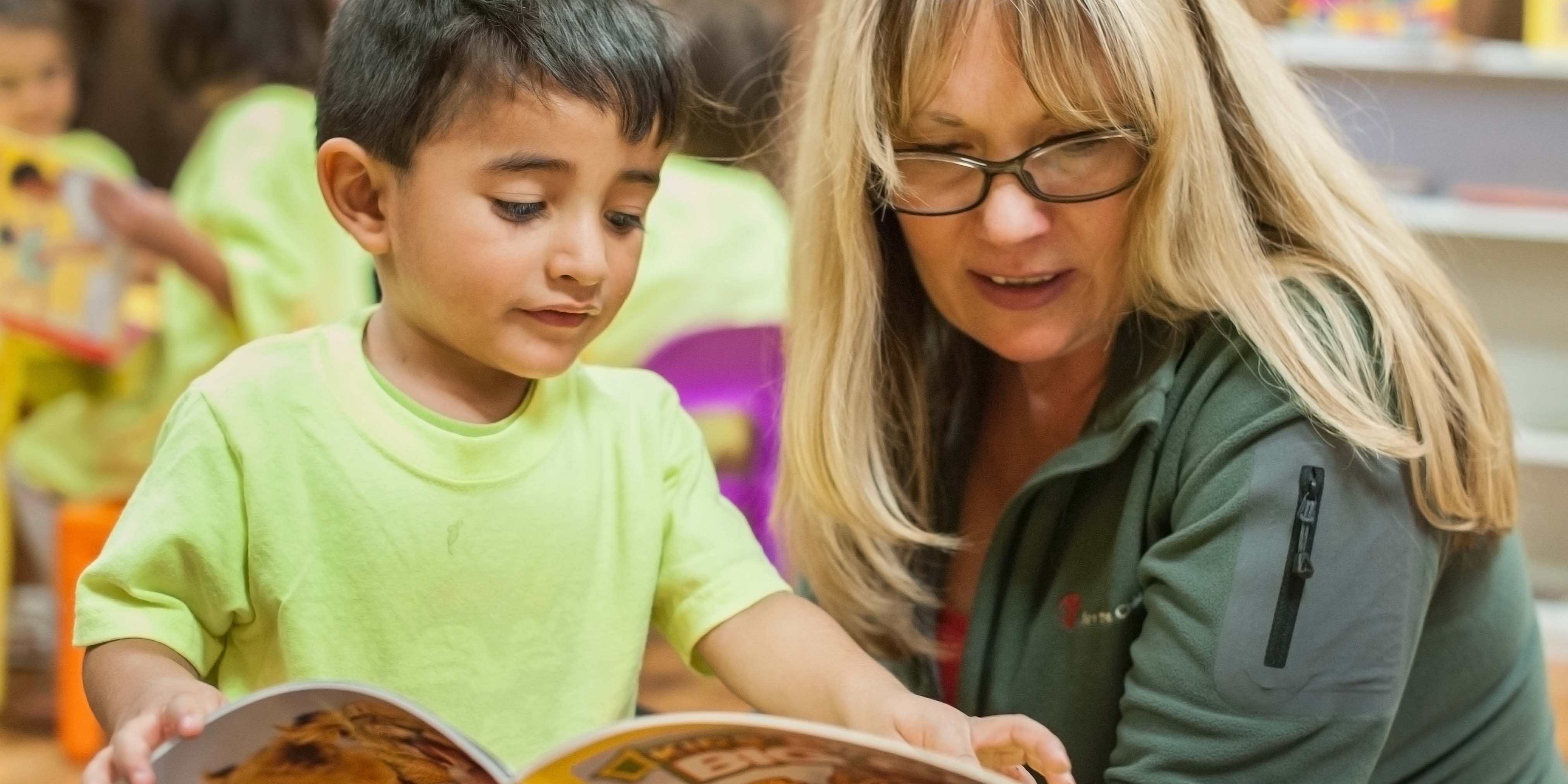Save the Children US staff member reads a book with adorable 3 yr. old boy