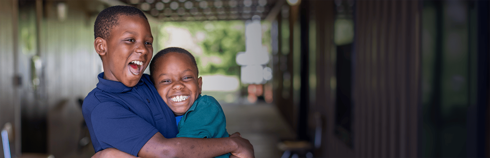 USA, 2 young boys, one in a blue shirt and the other a green shirt, smile as they hug. USA, 2 young boys, one in a blue shirt and the other a green shirt, smile as they hug.