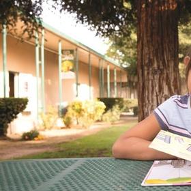 A girl reads outside at a picnic table A girl reads outside at a picnic table